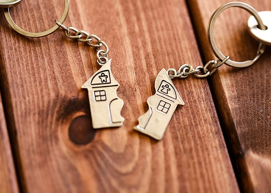Two halves of a home keyholders as a concept of property sale after divorce. — Ms. Li // Shutterstock