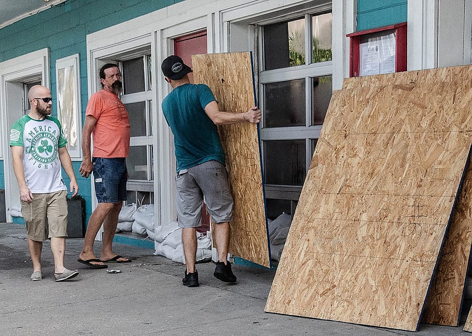 A group of workers board restaurant windows in preparation for a hurricane. — Prentiss Findlay // Shutterstock