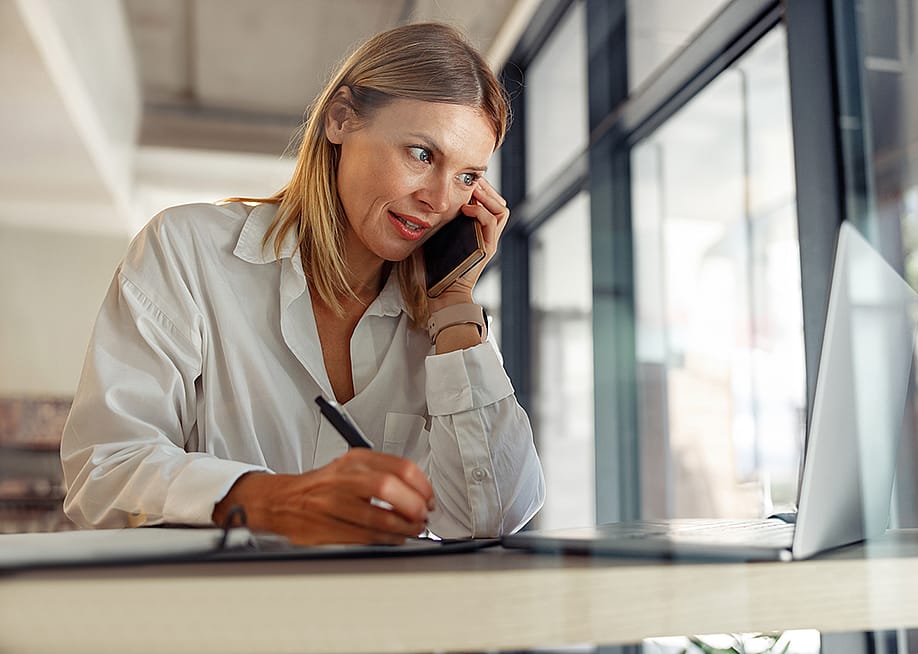A businesswoman writing down notes as she talks to someone on the phone. — Kostiantyn Voitenko // Shutterstock