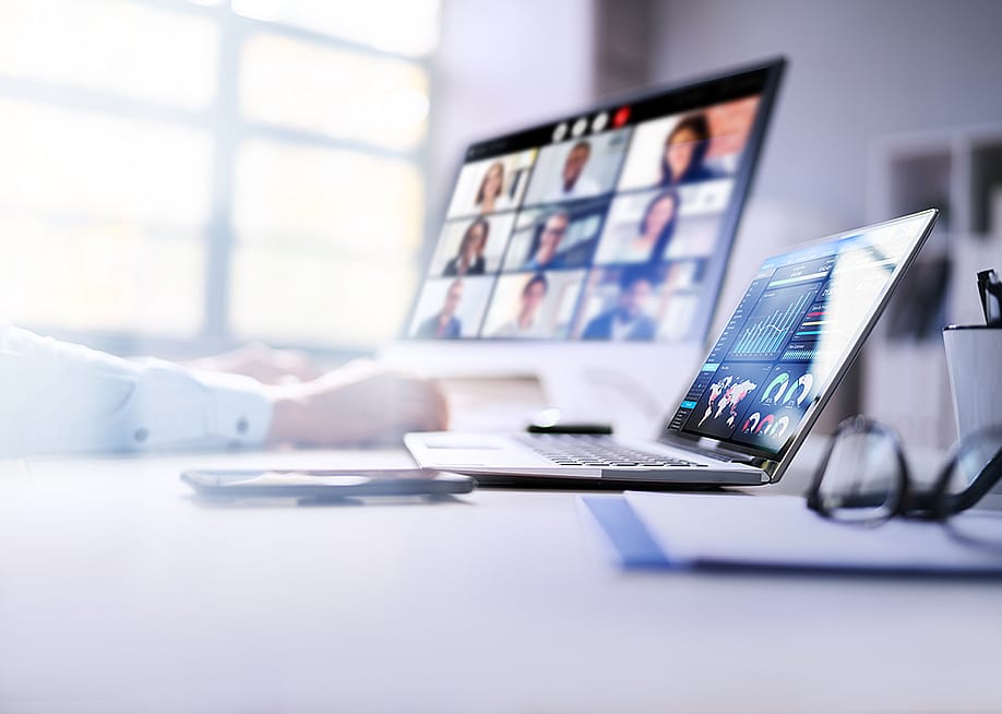 An employee's laptops at work displaying dashboards and a virtual video call. — Andrey_Popov // Shutterstock