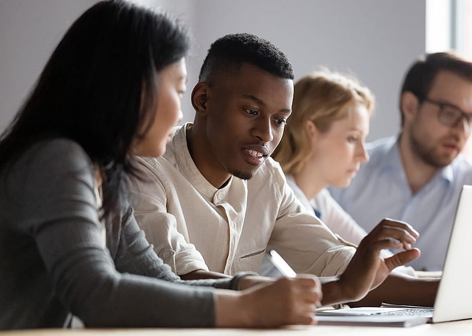 Colleagues seated at a desk in a co-working room. — fizkes // Shutterstock