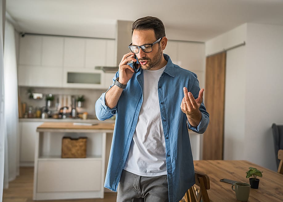 A man at home talking on the phone. — Miljan Zivkovic // Shutterstock