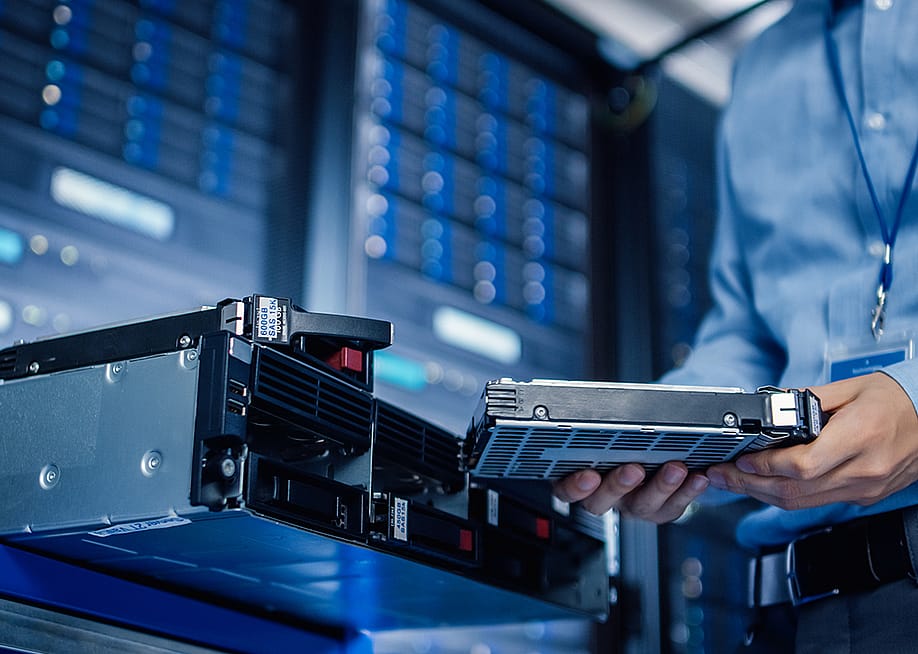 An IT engineer preparing to install new hardware into a server pack. — Gorodenkoff // Shutterstock