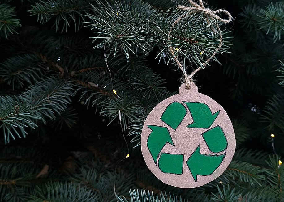 A recycling symbol ornament on a Christmas tree. — Rrrastalove // Shutterstock