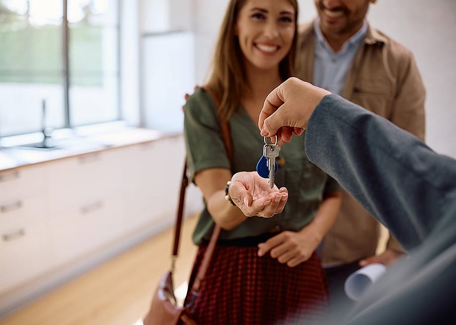 A real estate agent handing over house keys to a new couple. — Drazen Zigic // Shutterstock