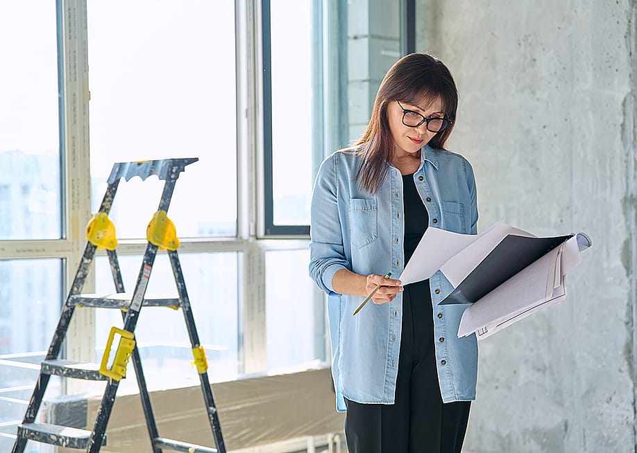 A female interior designer reviewing an apartment renovation plan. — VH-studio // Shutterstock