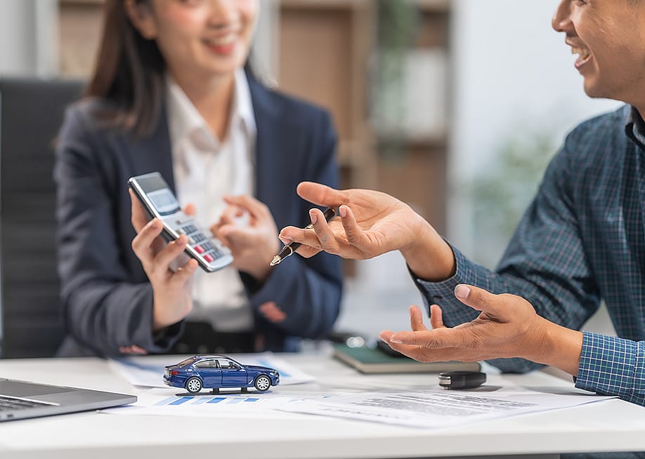 A car loan agent showing a client a sample computation. — PanuShot // Shutterstock