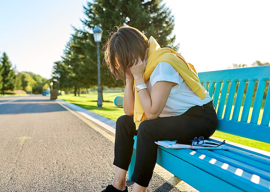 A tired woman sitting on a bench in the park, taking a break from fitness run. — VH-studio // Shutterstock