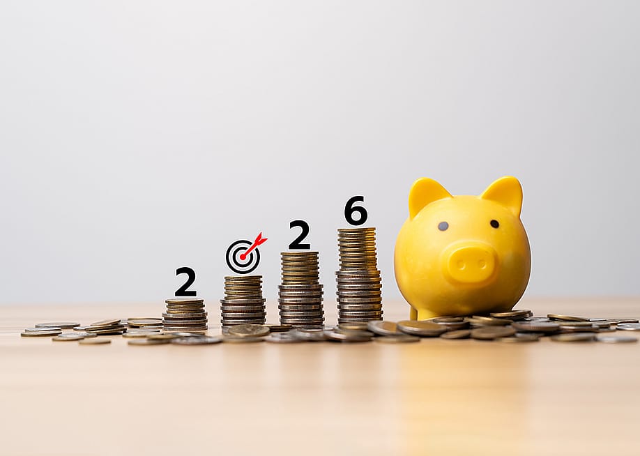 2026 target savings represented by a yellow piggy bank and a row of stacked coins. — Sutthiphong Chandaeng // Shutterstock