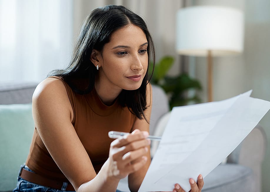 Woman checking bills in the living room. — PeopleImages // Shutterstock