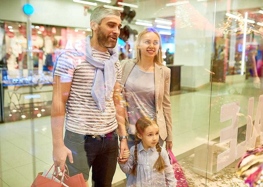 A happy family looking at window displays while shopping at a mall. — SeventyFour // Shutterstoc