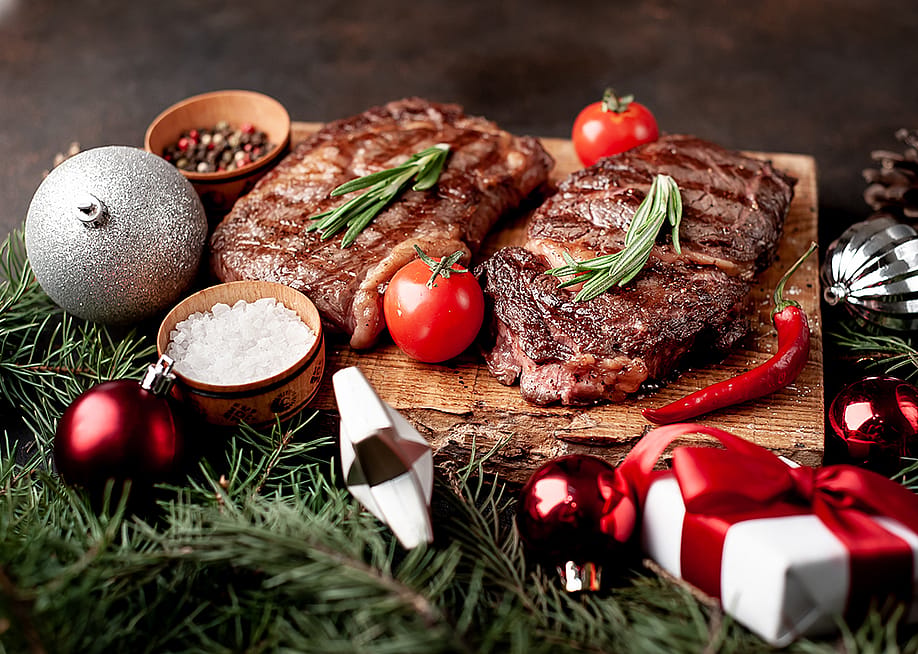 Beautifully grilled ribeye steaks prepared on a wooden board for Christmas. — aleksandr talancev // Shutterstock
