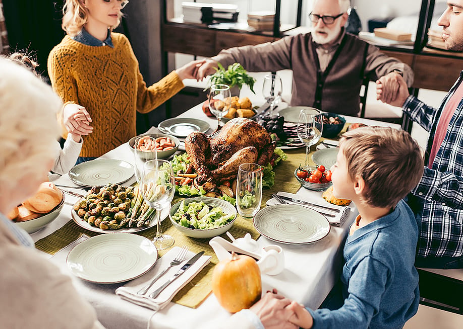 A family praying over their holiday dinner. — LightField Studios // Shutterstock