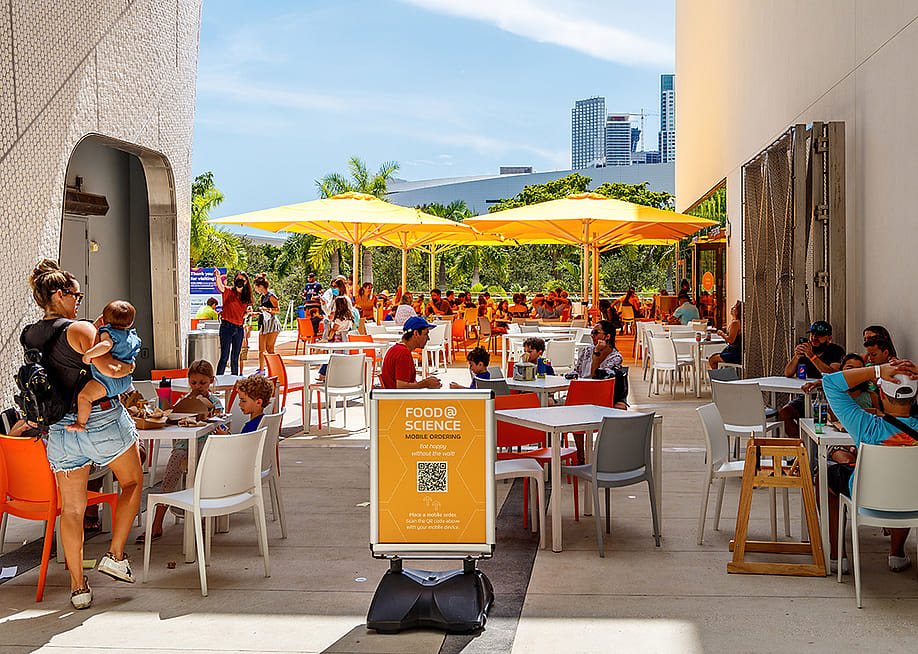 Outdoor dining areas at the Frost Museum in Florida where QR codes are seen for information and menu access. — Microfile.org // Shutterstock