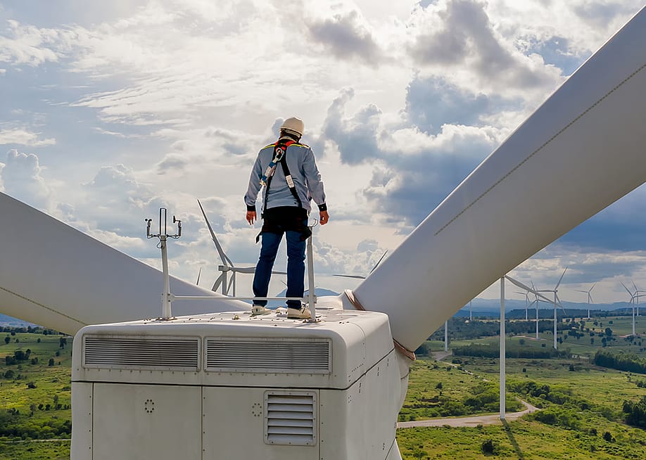 A windmill engineer on top of a wind turbine for inspection. — Bannafarsai_Stock // Shutterstock