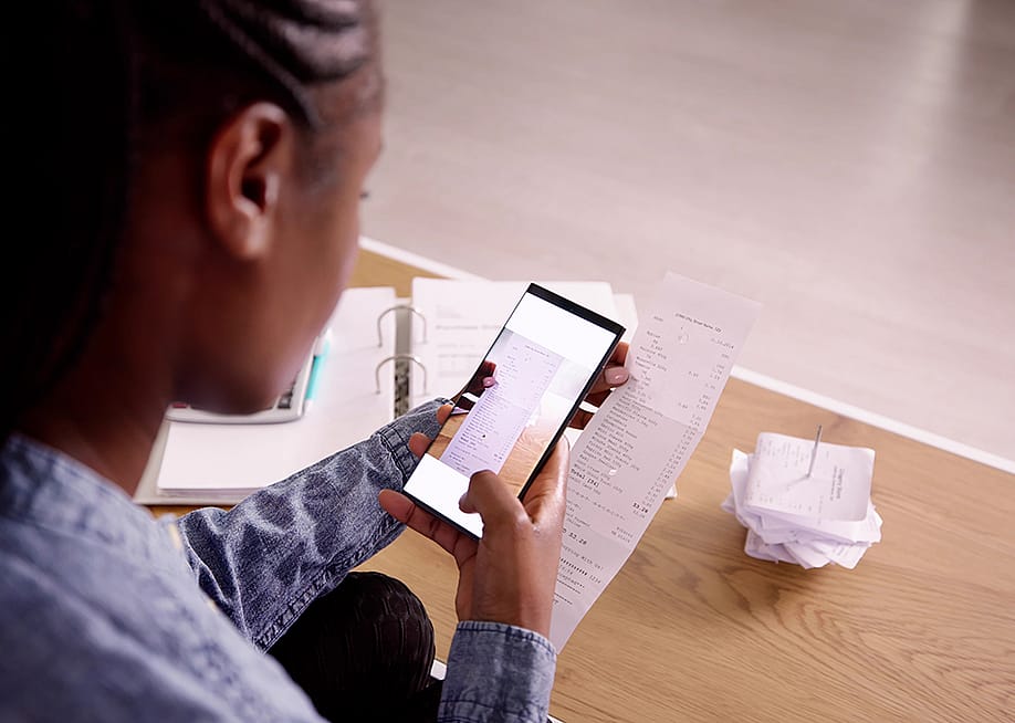 A woman taking a photo of a receipt using her phone. — Andrey_Popov // Shutterstock