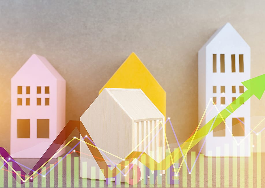 Colorful wooden figures of homes illustrated with finance chart graphics. — chaythawin // Shutterstock