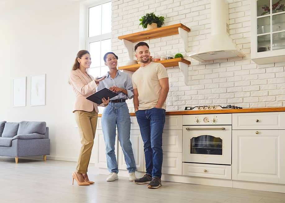 A female broker giving a young couple a tour of a house. — Studio Romantic // Shutterstock