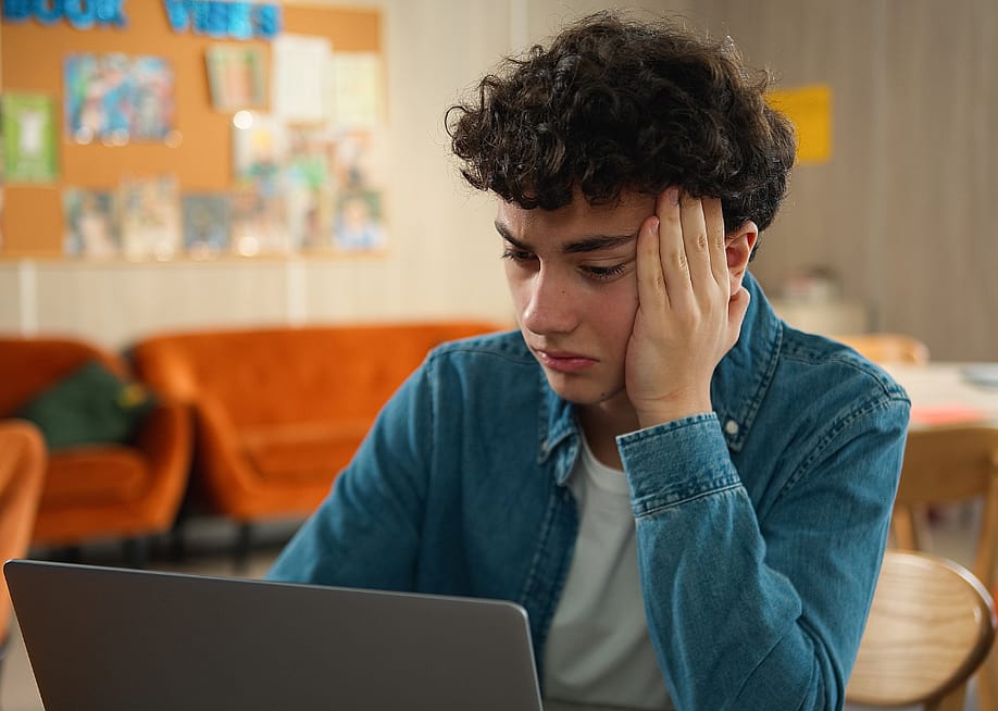 A stressed young adult sitting in front of a laptop. — MAYA LAB // Shutterstock