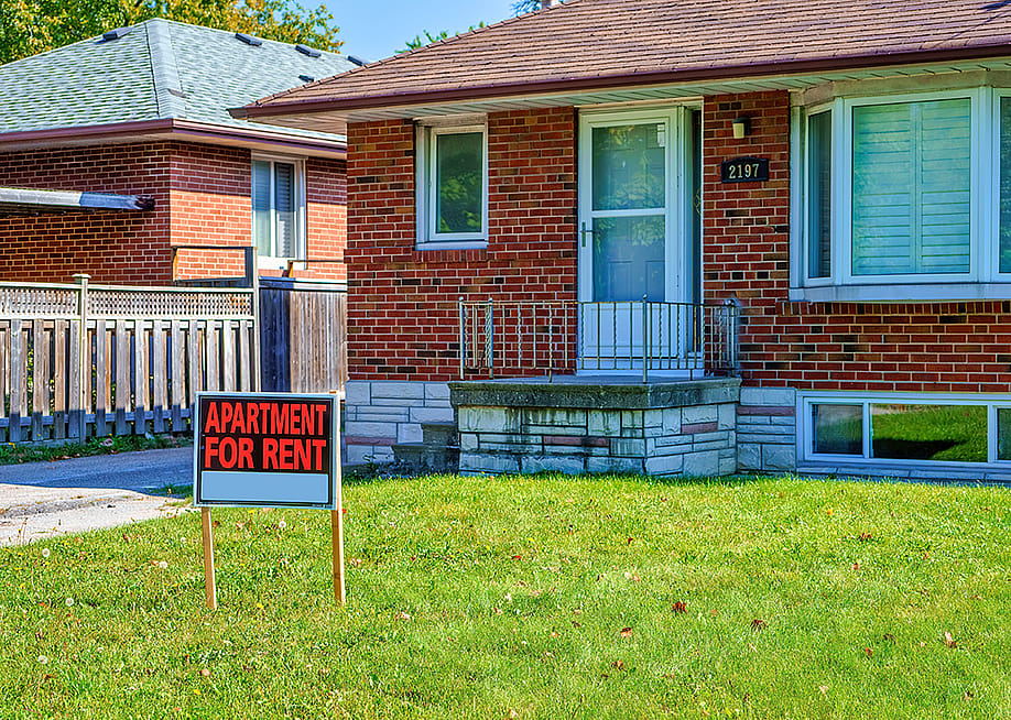 An 'apartment for rent' sign on a house lawn. — BobNoah // Shutterstock