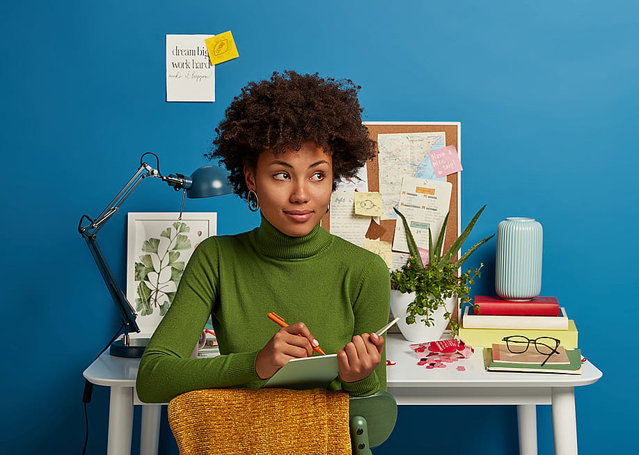 A young woman writing down plans in her notepad. — Cast Of Thousands // Shutterstock