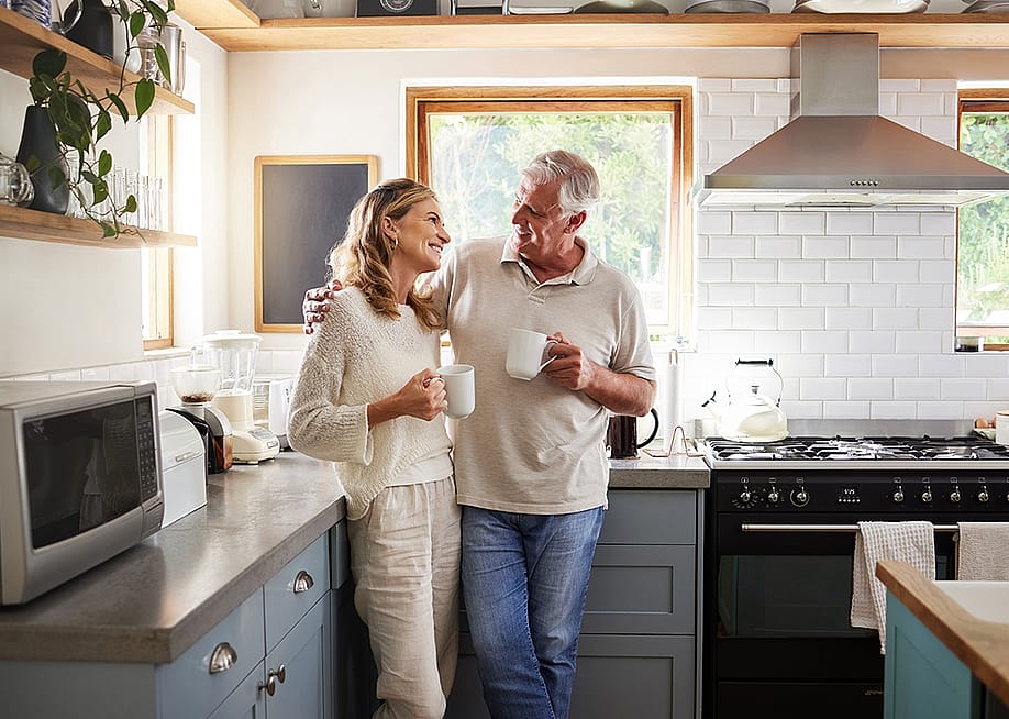 A middle-aged couple having a coffee in their kitchen. — PeopleImages // Shutterstock