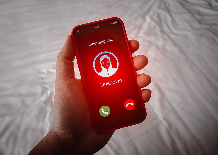 A person's smartphone receiving an unknown call with a red alert. — tete_escape // Shutterstock