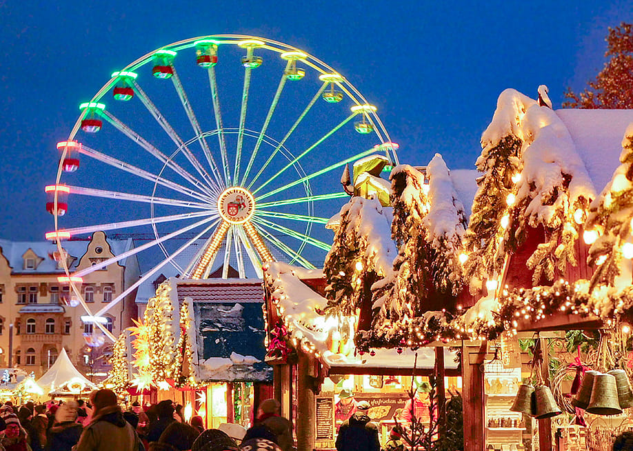 A ferris wheel lights up the night sky during twilight at the Erfurt Christmas Market with vendors selling festive goods in the foreground. — Historic Highlights of Germany