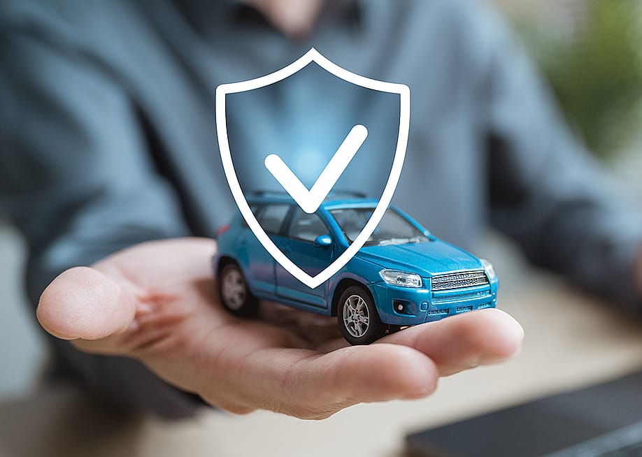 Person holding a small figure of a car illustrated with a shield as a concept of car insurance. — Garun .Prdt // Shutterstock
