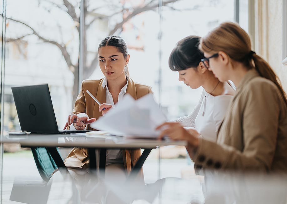 A group of three female professionals in a coworking space. — Gorgev // Shutterstock