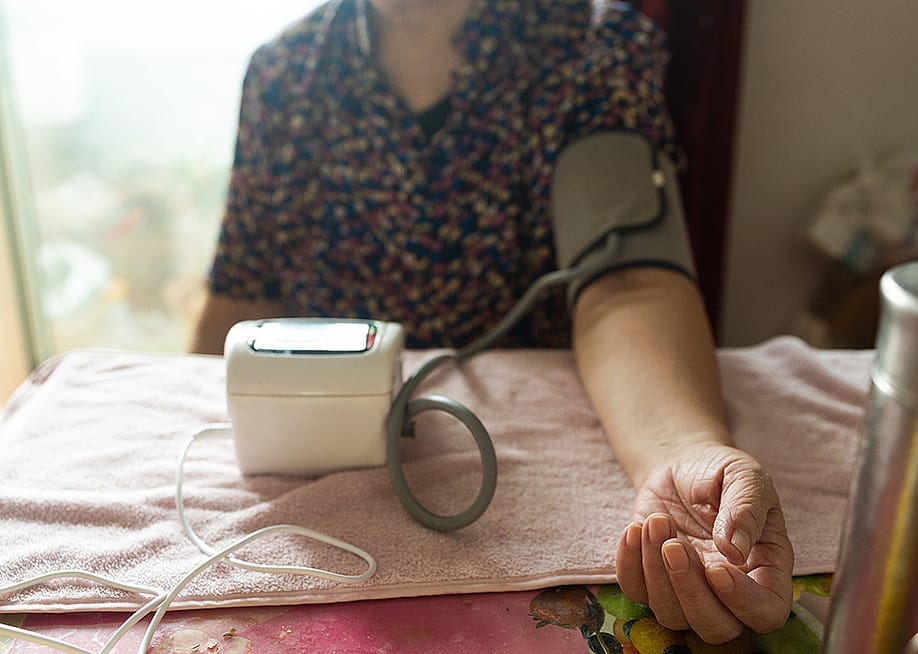 A senior woman getting her blood pressure checked using a digital monitor. — Yanya // Shutterstock