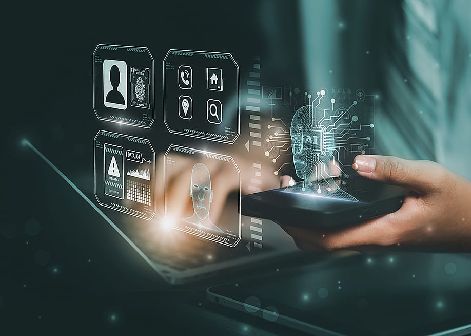 AI and facial recognition graphics illustrated over a person using a laptop and smartphone. — ART STOCK CREATIVE // Shutterstock