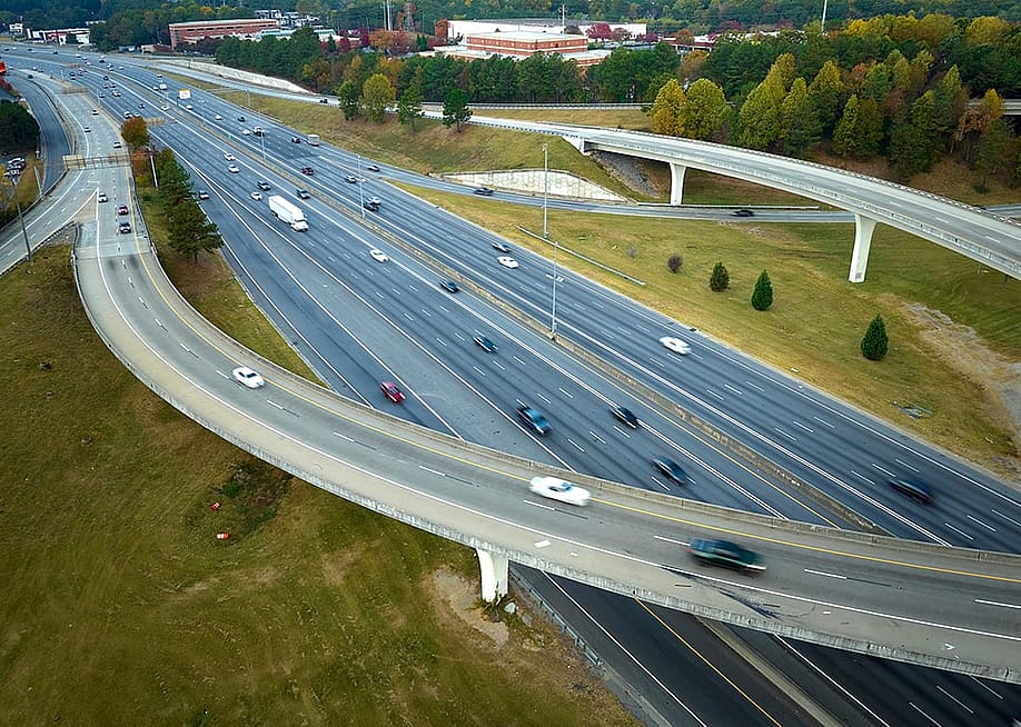 An aerial view of an American freeway intersection with fast moving trucks and cars. — Bilanol // Shutterstock