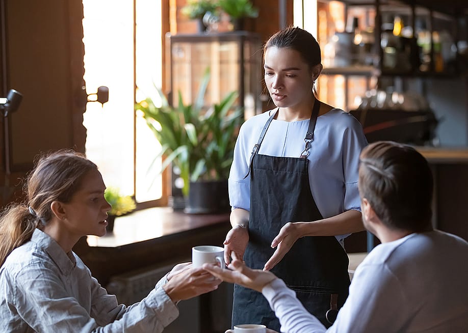 An angry couple disputing a complaint with a cafe waitress. — fizkes // Shutterstock
