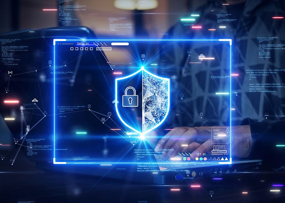 A person's hands type on a computer keyboard with a glowing security shield overlaid on the photo. — Ar_TH // Shutterstock