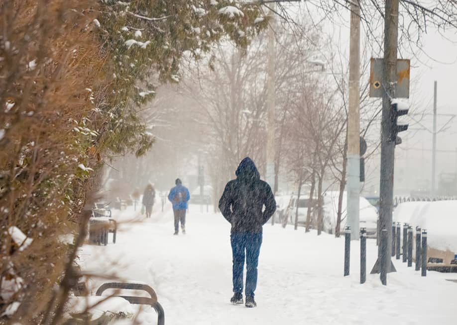 People walking through sidewalks during a heavy snowfall day. — RecCameraStock // Shutterstock