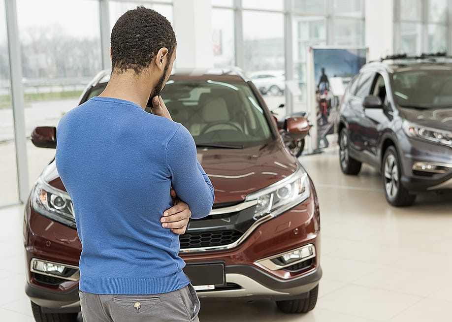 Rear view of a man choosing a car at a dealership. — Zoriana Zaitseva // Shutterstock