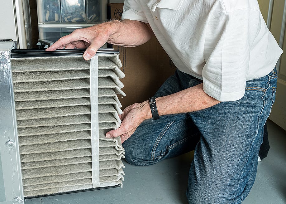 Man changing a folded dirty air filter of an HVAC system. — Steve Heap // Shutterstock