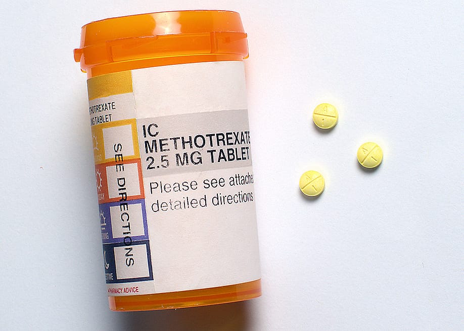 Three generic Methotrexate pills beside a prescription bottle. — Ray Geiger // Shutterstock