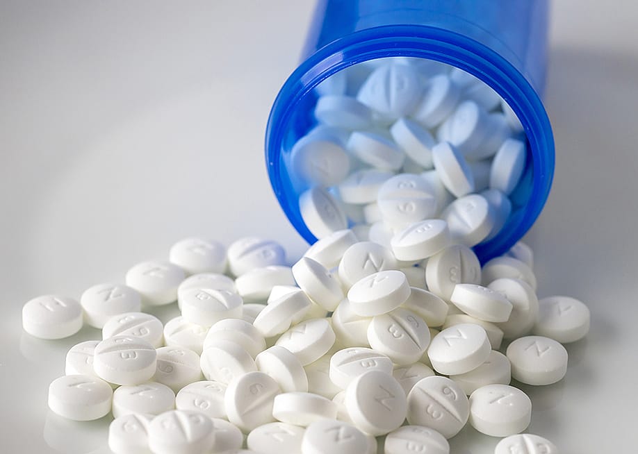 Metformin pills spilling out of a blue prescription bottle. — Nalidsa // Shutterstock