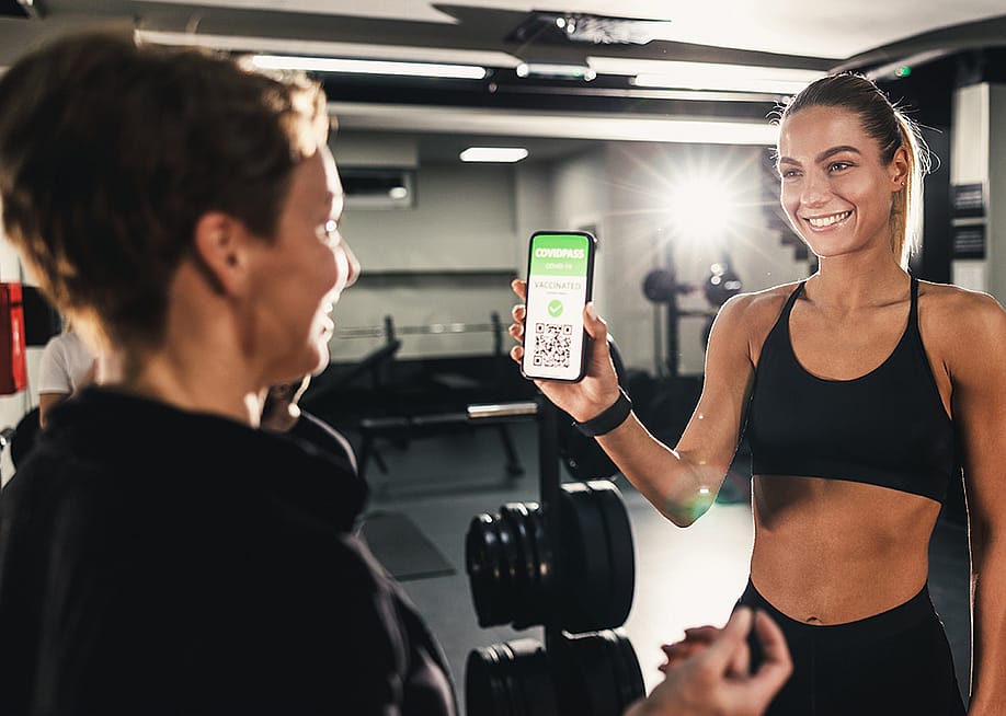 A female gym client showing a gym employee her QR code proof of COVID-19 vaccination. — MilanMarkovic78 // Shutterstock