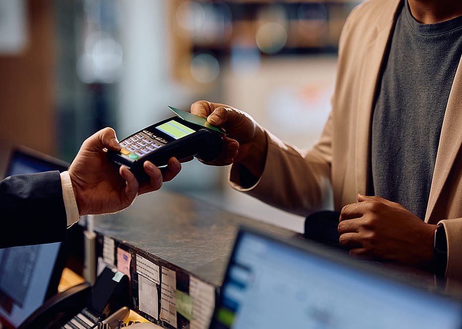 Person taps credit card on a payment terminal at a hotel. — Drazen Zigic // Shutterstock