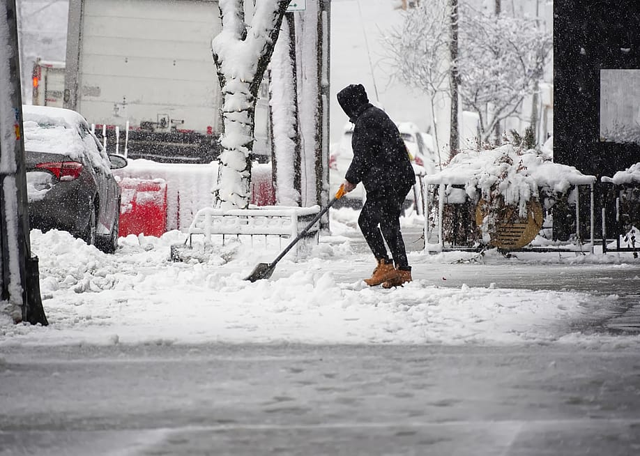 A person shovels snow in a neighborhood. — John Hanson Pye // Shutterstock