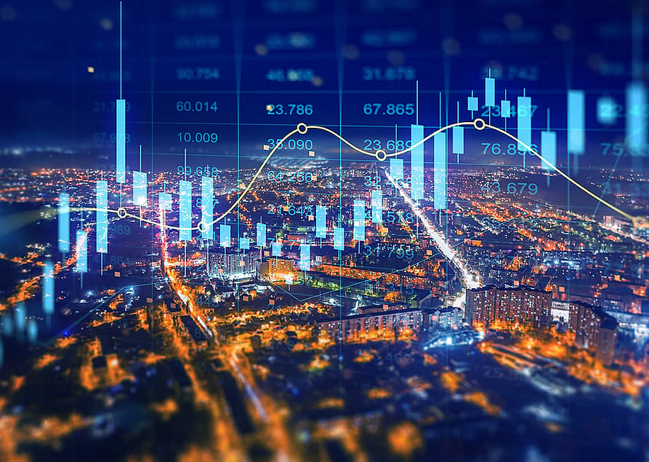 Aerial view of a city at night illustrated with holographic finance charts. — Miha Creative // Shutterstock