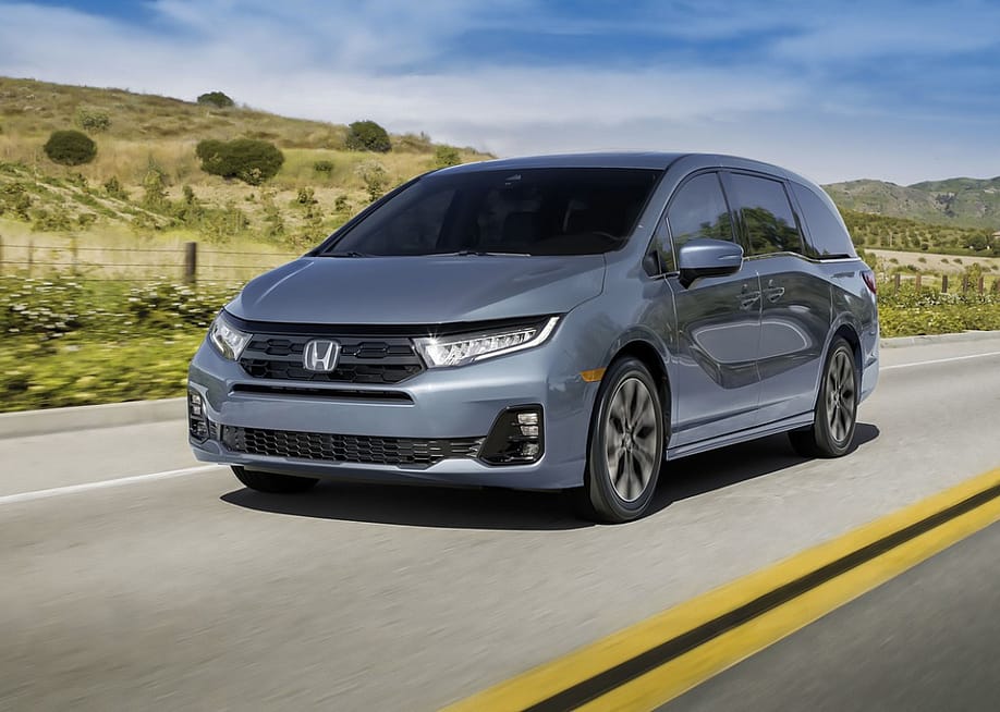 A dark gray Honda Odyssey driving down a rural road. — Honda