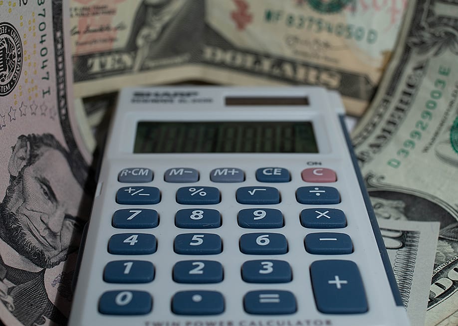 A calculator with a background of US dollar banknotes. — Thomas Martin-Creuzot // Shutterstock