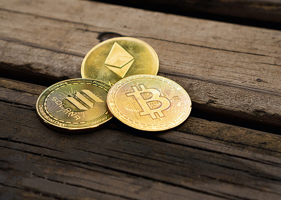 Gold crypto coins on a wooden surface. — Diego Thomazini // Shutterstock