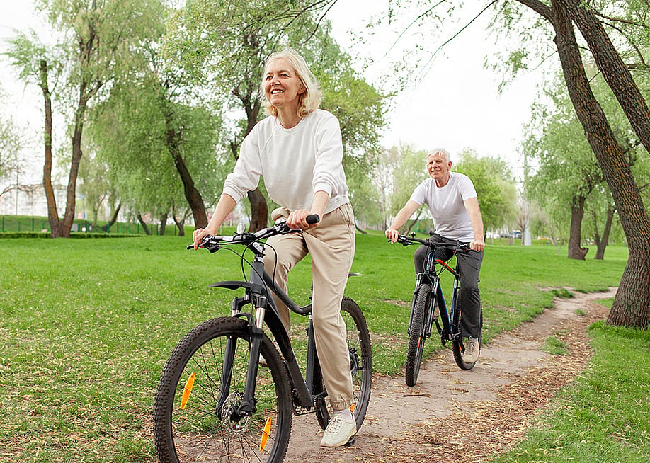 A senior couple riding bikes in a park. — Bohdan Malitskiy // Shutterstock