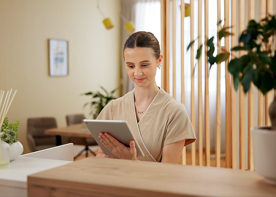 A female front desk staff at a spa using a digital tablet to look at schedule. — PeopleImages // Shutterstock