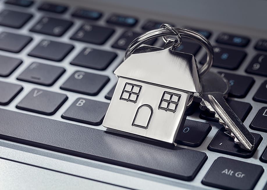 A house key and steel house keychain on top of a laptop keyboard. — Brian A Jackson // Shutterstock